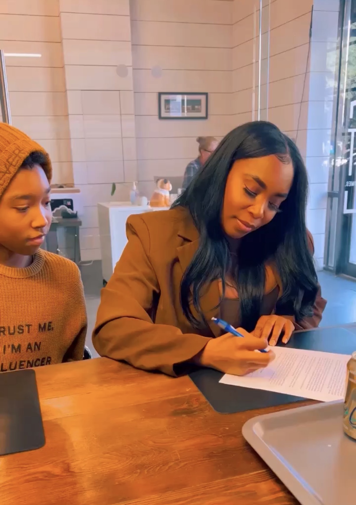 India signing closing paperwork with her son beside her