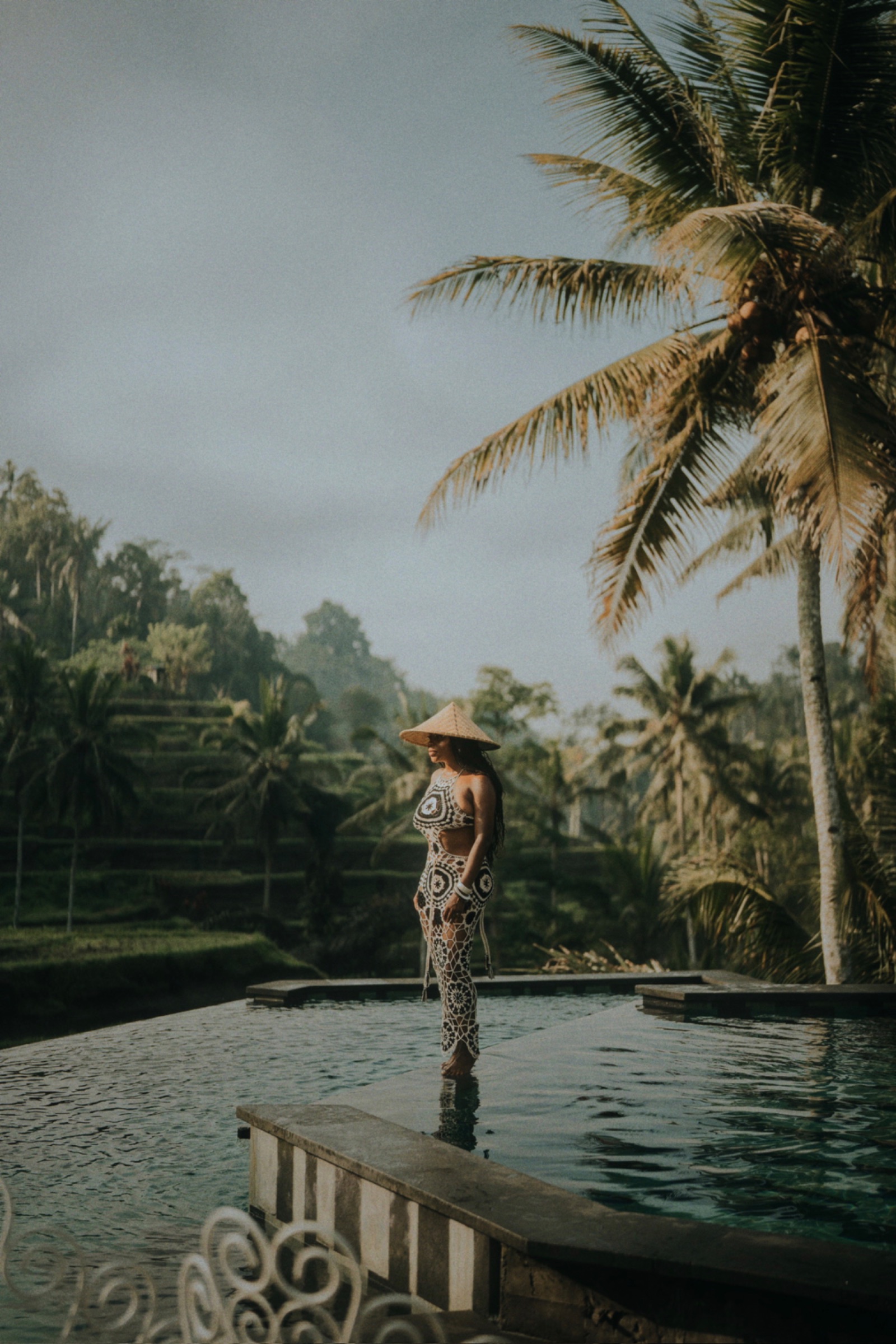 India standing on the edge of an infinity pool above the Bali jungle — work made optional