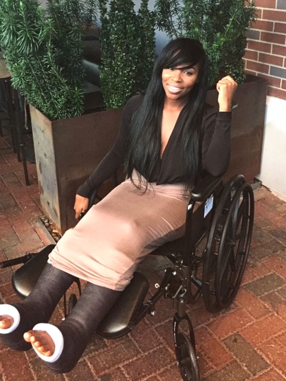 India in a wheelchair, both legs in casts, fist raised — the start of the comeback